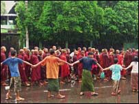 Onlookers holding hands as monks walk by